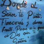 Blue wall hand-painted with a Spanish religious saying, 'Donde el Señor te planta, florecerás', and Christmas ornaments