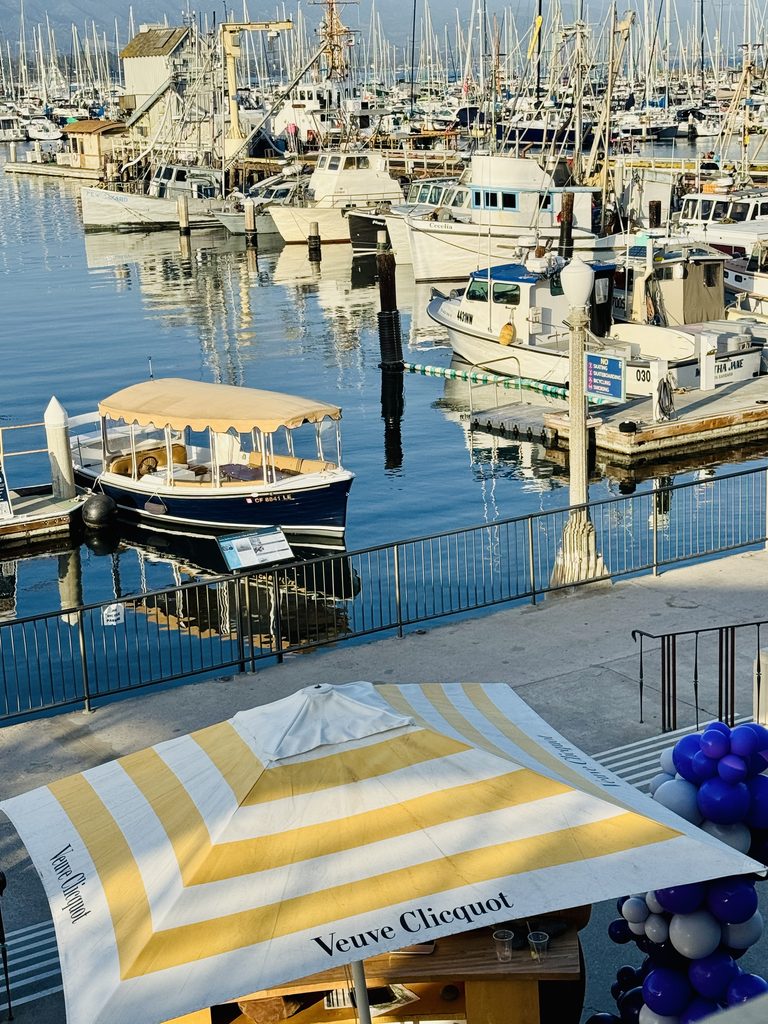 Fishing boats and yachts in Santa Barbara harbour, with a Veuve Clicquot parasol and purple balloons in front