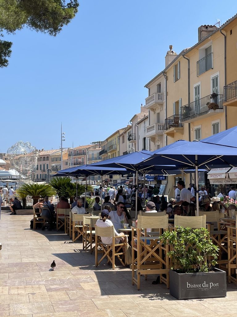 Bistrot du Port terrace in Saint-Tropez, with navy parasols and wooden chairs along a sunny quayside