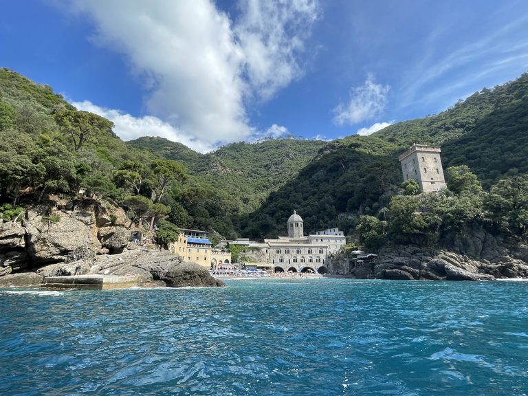 Secluded cove with a domed abbey, a square stone watchtower and a small beach, backed by steep wooded hills